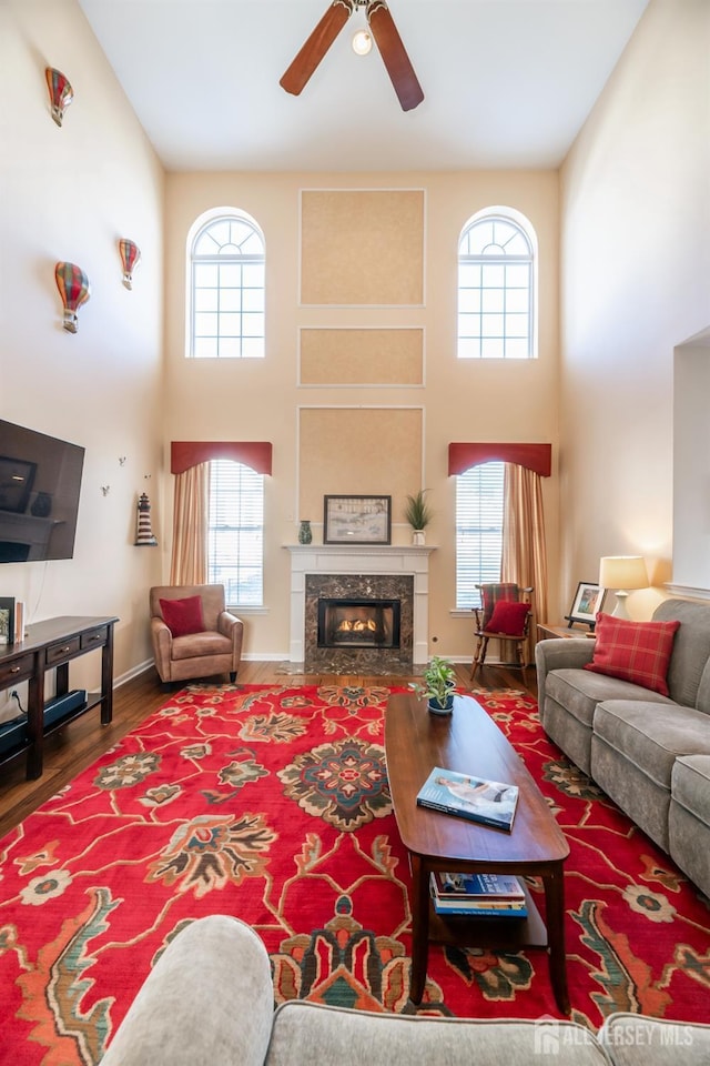 living room with hardwood / wood-style floors, a fireplace, a high ceiling, and plenty of natural light