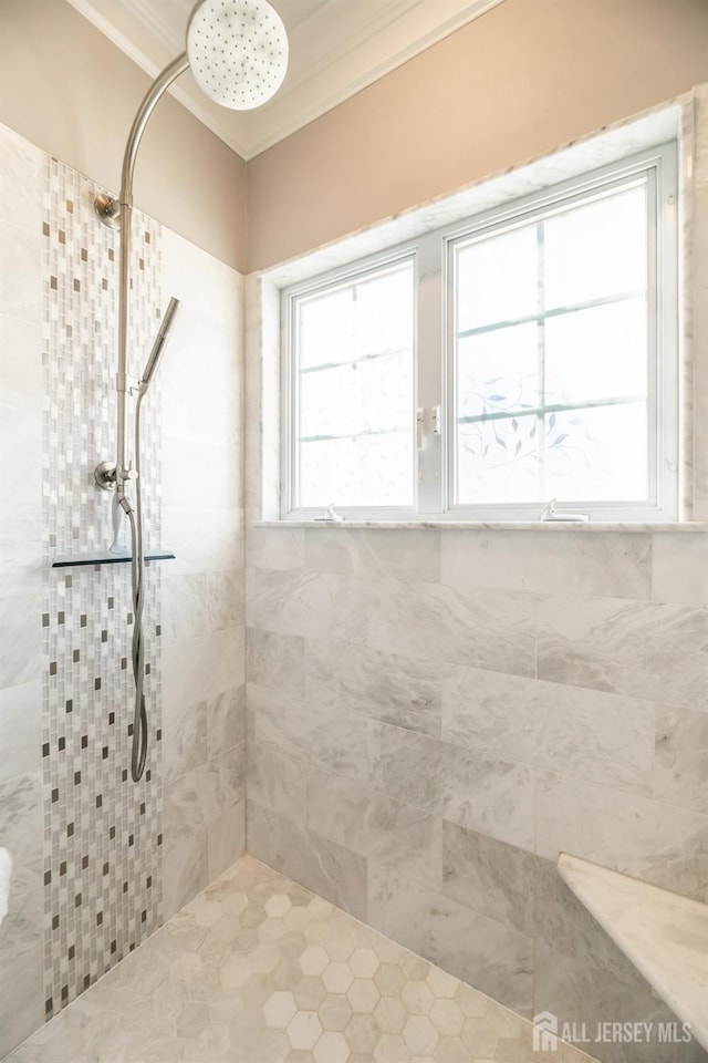 bathroom featuring a tile shower and crown molding