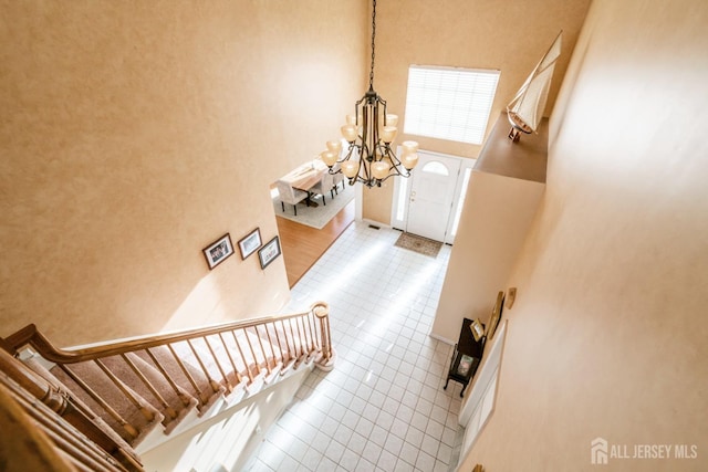 stairs featuring an inviting chandelier, tile patterned floors, and a high ceiling