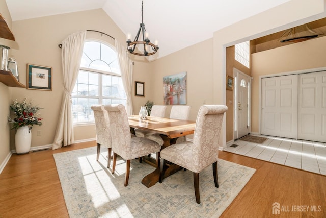 dining space featuring lofted ceiling, a notable chandelier, and light wood-type flooring