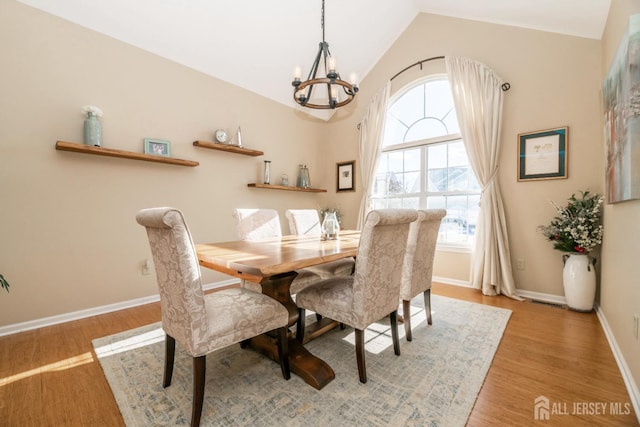 dining room with lofted ceiling, a chandelier, and light hardwood / wood-style flooring