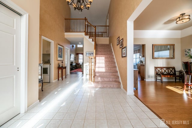 tiled entryway featuring a towering ceiling and a chandelier