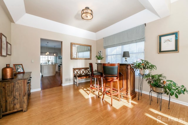 dining area with light hardwood / wood-style floors and a tray ceiling