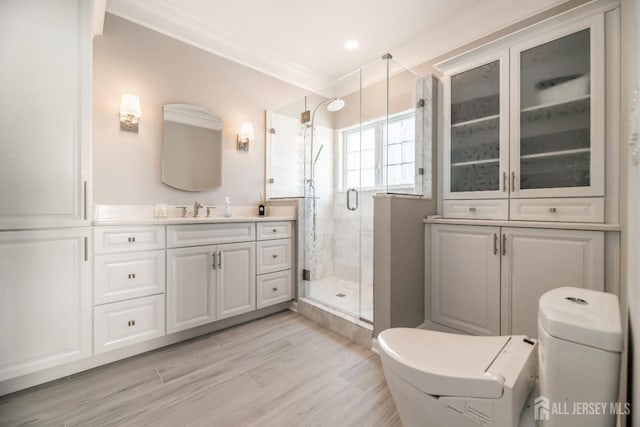 bathroom with ornamental molding, a shower with shower door, vanity, and toilet