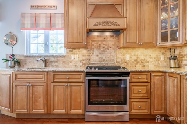 kitchen featuring light stone counters, sink, decorative backsplash, and stainless steel range oven