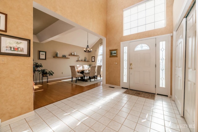 foyer entrance with an inviting chandelier, light tile patterned floors, and high vaulted ceiling