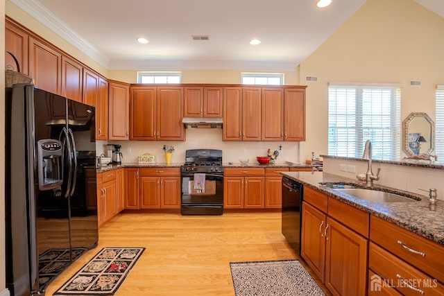 9 Copernicus Ct, East Windsor, NJ 08512 - kitchen with black appliances, dark stone counters, brown cabinets, light wood-style floors, and under cabinet range hood