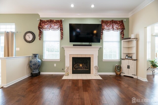 unfurnished living room with wood finished floors, a tile fireplace, ornamental molding, baseboards, and recessed lighting