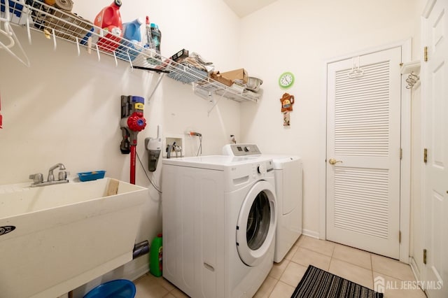 laundry area with washing machine and clothes dryer and light tile patterned floors