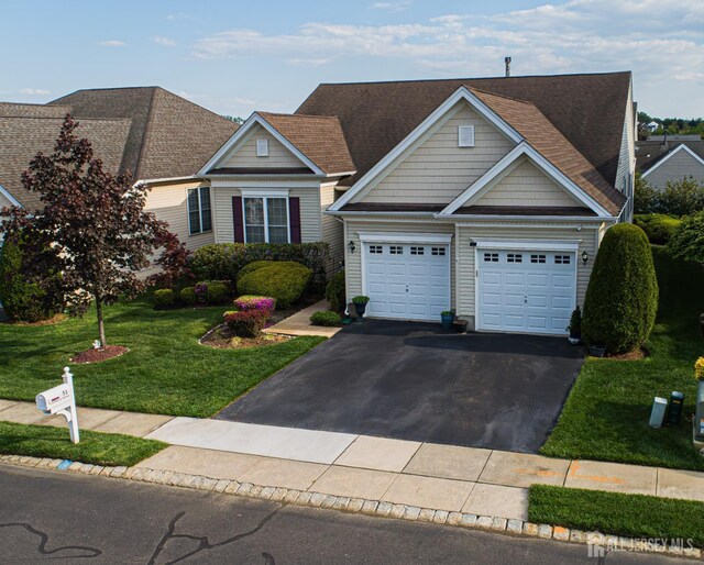 view of front of house featuring asphalt driveway, a front yard, a shingled roof, and a garage