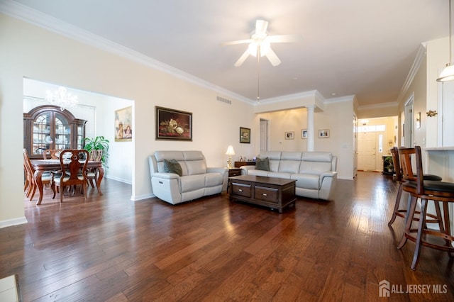 living area with dark wood-type flooring, baseboards, ceiling fan, ornamental molding, and a chandelier
