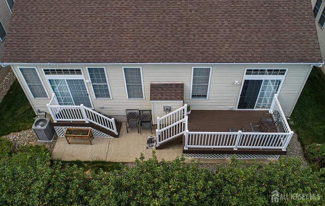 back of house with a shingled roof, a wooden deck, and central AC