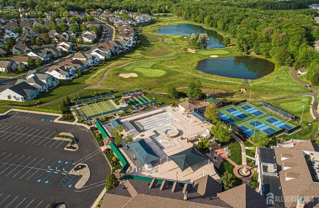 aerial view of property's location featuring a nearby body of water, nearby suburban area, and a local golf course
