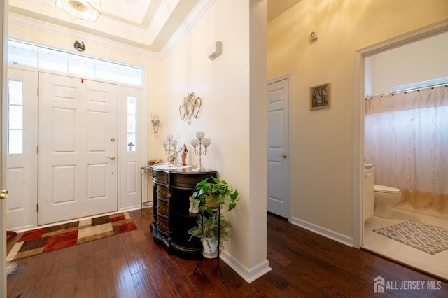 foyer featuring hardwood / wood-style flooring, crown molding, and baseboards