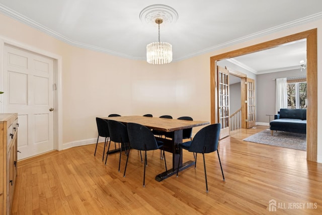 dining room with a chandelier, light wood finished floors, ornamental molding, and baseboards