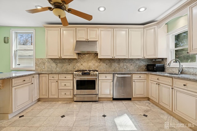 kitchen featuring stainless steel appliances, cream cabinetry, and recessed lighting
