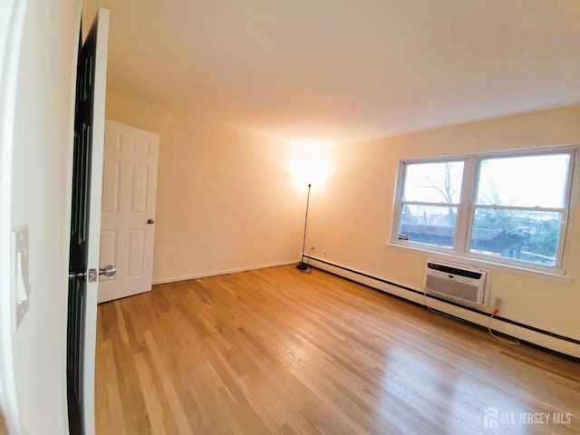 spare room with baseboard heating and light wood-style floors