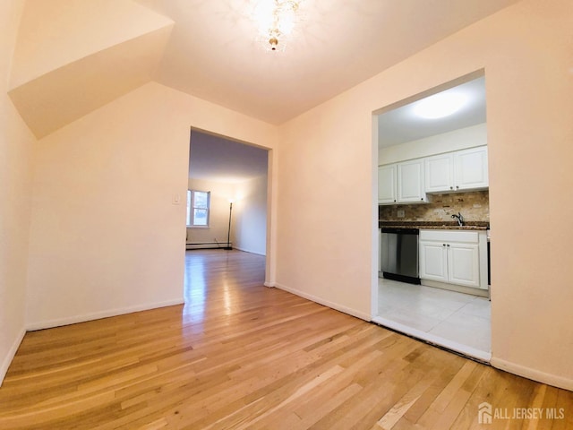 interior space with baseboards, lofted ceiling, baseboard heating, light wood-style floors, and a sink