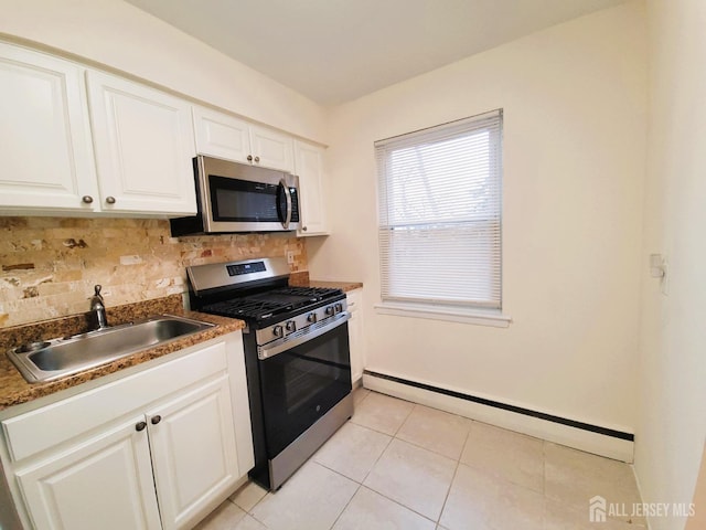 kitchen with light tile patterned floors, a baseboard heating unit, a sink, appliances with stainless steel finishes, and tasteful backsplash