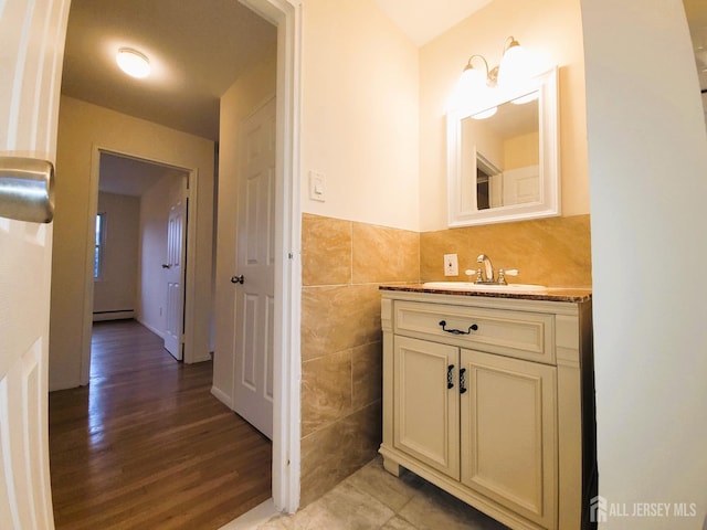 bathroom with a baseboard radiator, tile walls, vanity, and wood finished floors