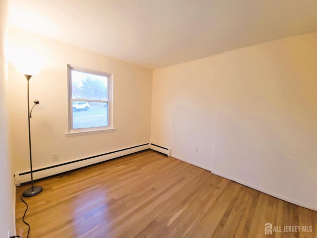 empty room featuring a baseboard radiator and wood finished floors