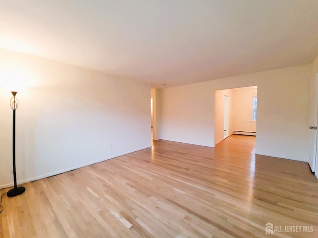 empty room featuring light wood finished floors and baseboard heating