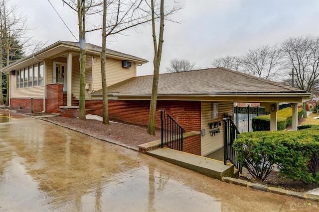 exterior space featuring a shingled roof and brick siding