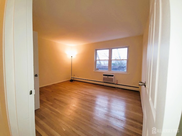 unfurnished room featuring baseboard heating and wood finished floors