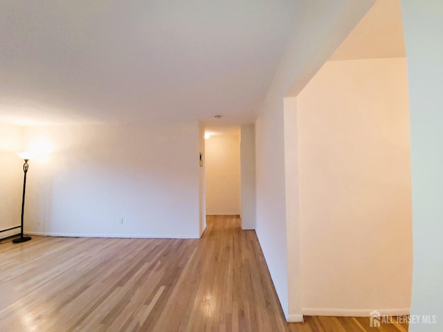 unfurnished room with light wood-type flooring and baseboards