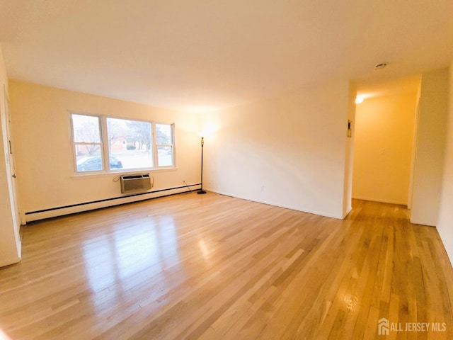 spare room featuring a wall unit AC, light wood-style floors, and baseboard heating