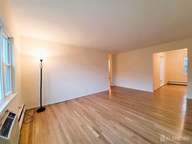 unfurnished room with light wood-type flooring and baseboard heating