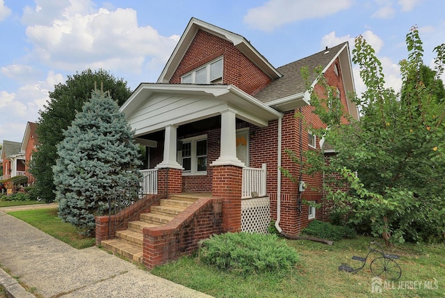 view of front of home featuring a shingled roof, a porch, and brick siding