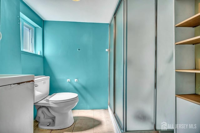 bathroom featuring a stall shower, tile patterned flooring, and toilet