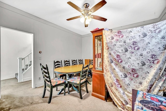 dining area with light carpet, baseboards, stairway, and ceiling fan