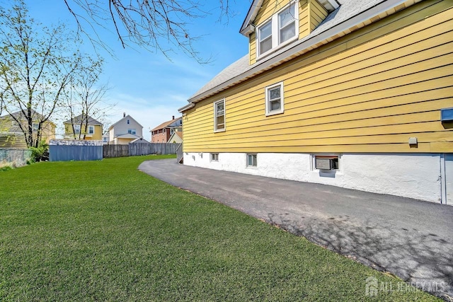 view of side of property featuring fence, a yard, and a residential view