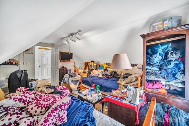bedroom featuring rail lighting and vaulted ceiling