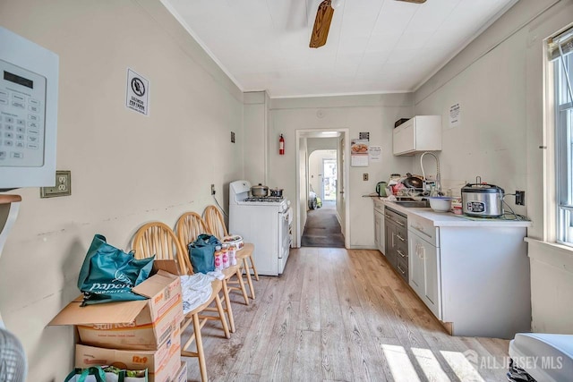 kitchen with white gas stove, light wood-type flooring, a wealth of natural light, and white cabinetry