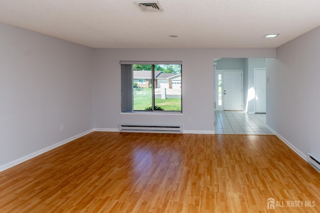 249 Doremus Dr Unit B, Monroe, NJ 08831 - empty room with a baseboard heating unit, light wood finished floors, baseboards, and a textured ceiling