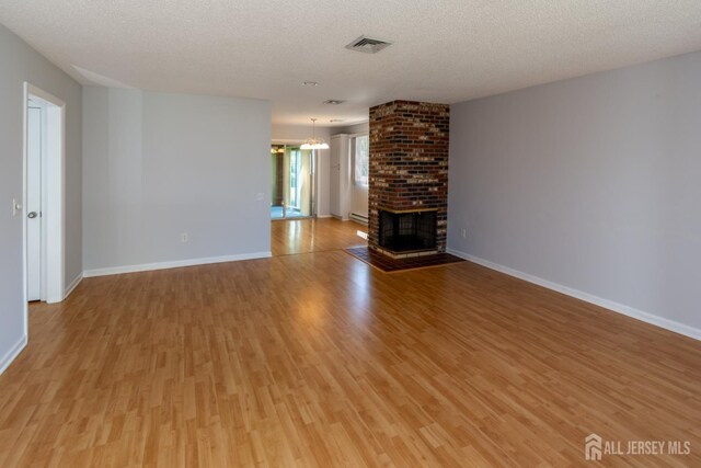 249 Doremus Dr Unit B, Monroe, NJ 08831 - unfurnished living room featuring light wood finished floors, a textured ceiling, baseboards, a baseboard heating unit, and a chandelier
