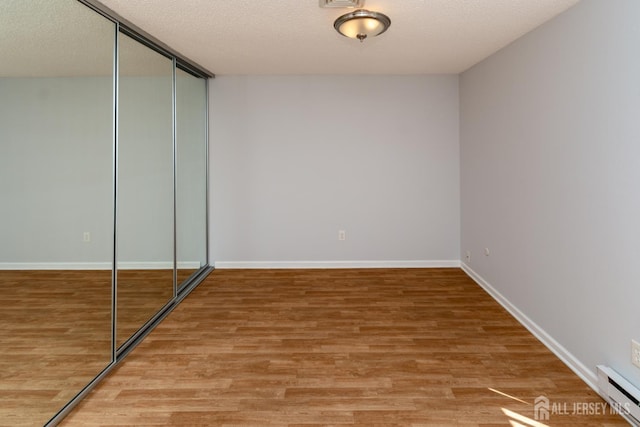 249 Doremus Dr Unit B, Monroe, NJ 08831 - unfurnished bedroom featuring a baseboard heating unit, light wood finished floors, a closet, baseboards, and a textured ceiling