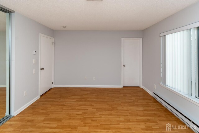 249 Doremus Dr Unit B, Monroe, NJ 08831 - spare room featuring a baseboard radiator, light wood-type flooring, plenty of natural light, and a textured ceiling