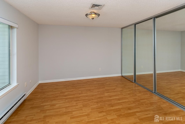 249 Doremus Dr Unit B, Monroe, NJ 08831 - unfurnished bedroom with baseboard heating, light wood-style floors, a closet, baseboards, and a textured ceiling