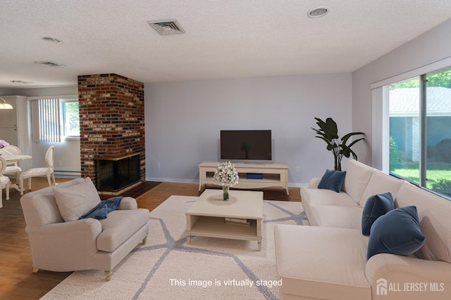 249 Doremus Dr Unit B, Monroe, NJ 08831 - living area featuring a textured ceiling, plenty of natural light, wood finished floors, a brick fireplace, and baseboards