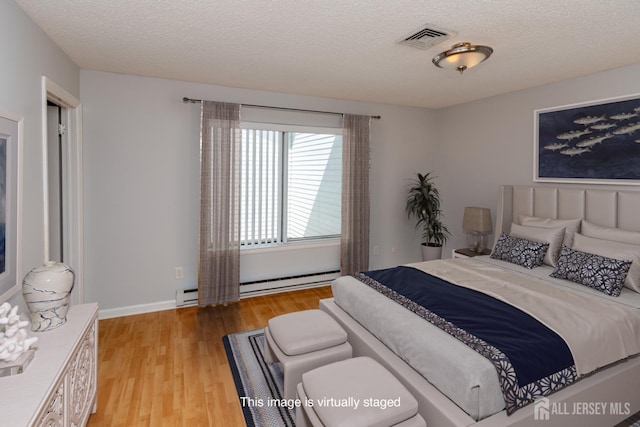 249 Doremus Dr Unit B, Monroe, NJ 08831 - bedroom featuring light wood-style flooring, a textured ceiling, a baseboard heating unit, and baseboards
