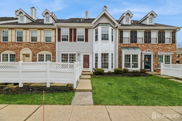 multi unit property featuring brick siding, a front yard, and fence