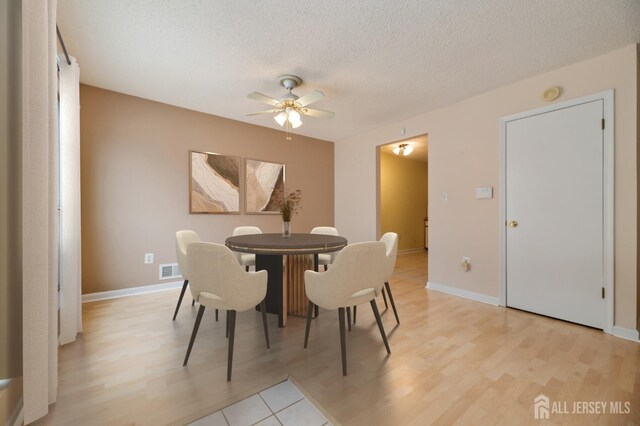 dining area featuring ceiling fan, a textured ceiling, and light wood-type flooring