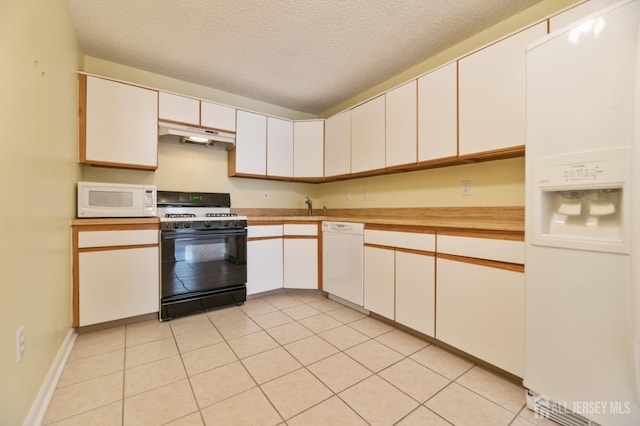 kitchen featuring white appliances, light tile patterned floors, a sink, under cabinet range hood, and a textured ceiling