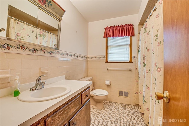 50 Lilac St, Edison, NJ 08817 - bathroom with tile walls, toilet, a wainscoted wall, vanity, and tile patterned floors