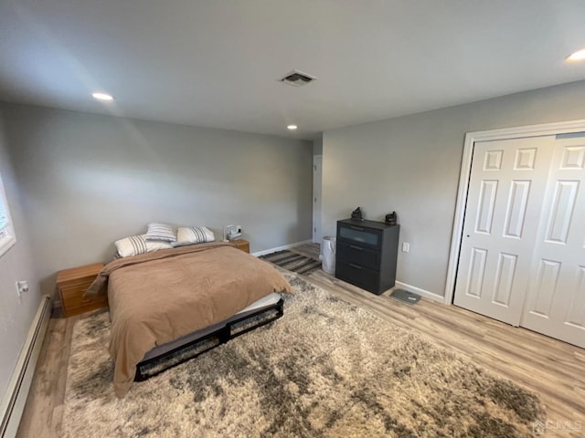 bedroom with a closet, a baseboard radiator, and light hardwood / wood-style floors