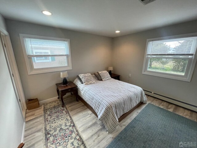 bedroom with baseboard heating and light hardwood / wood-style flooring